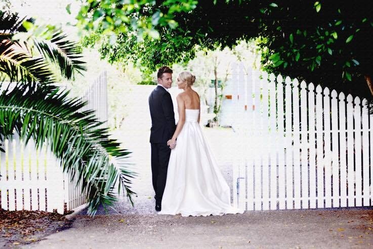 Bride and groom walking through the romantic white garden gate at Tudor Lodge