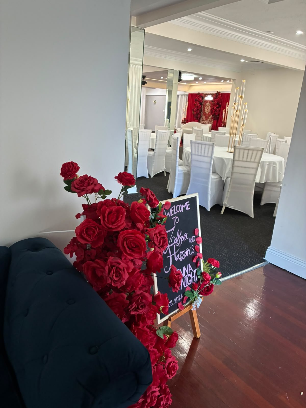 Rose-framed welcome easel sign at the entrance to the illuminated banquet dining hall