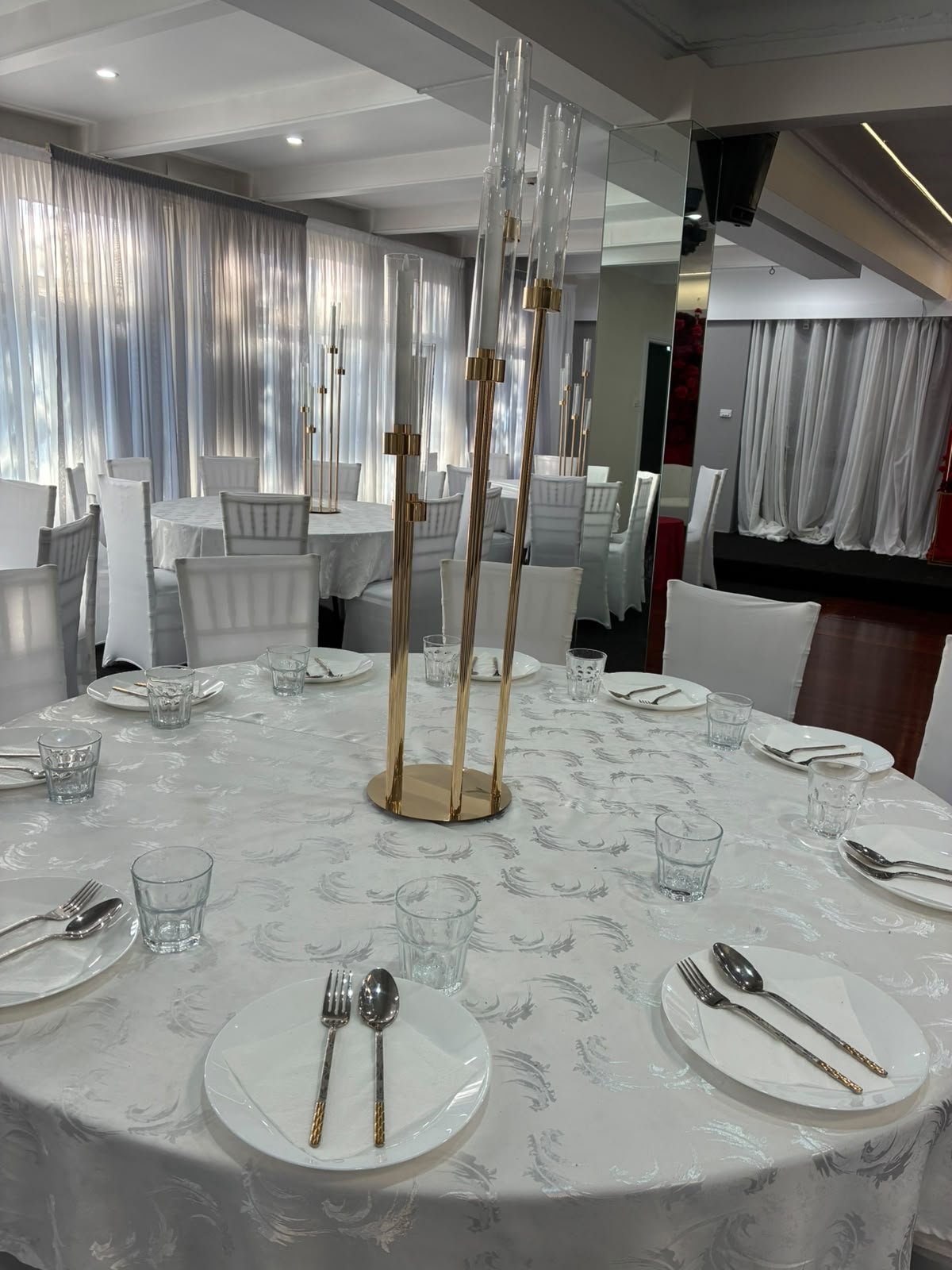 Grand banquet table setting with tall gold candelabras, crystal glassware, and embossed white damask linens