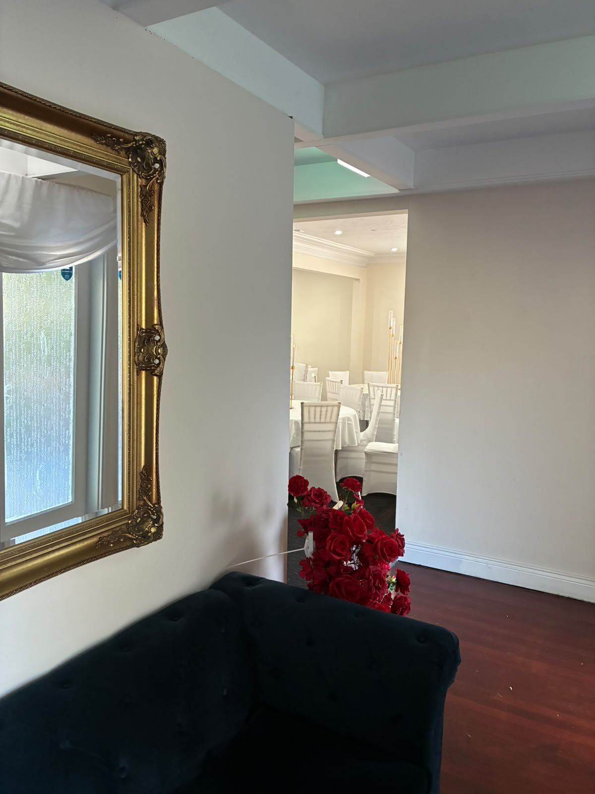 Historic manor foyer featuring an ornate gilded mirror, velvet lounge seating, and fresh red roses